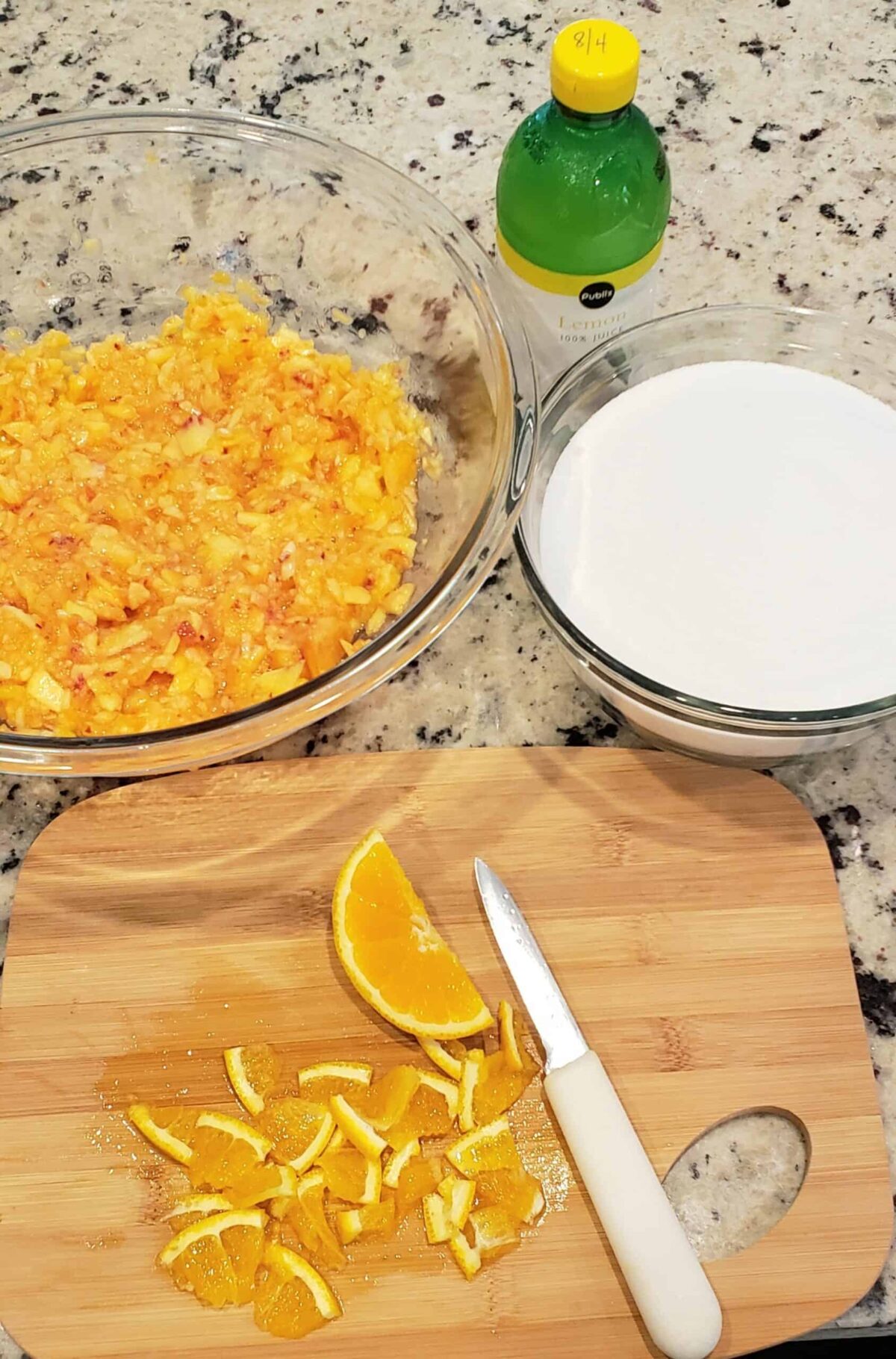 Slices of orange and a bowl of mashed peaches with a bowl of white sugar