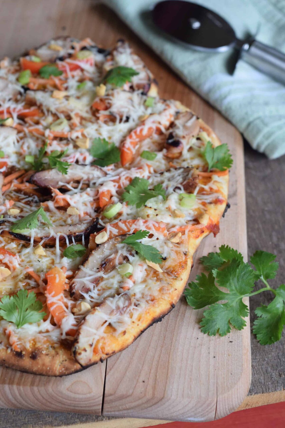 Thai Chicken Grilled Pizza made with Naan bread. Pizza wheel and cutting board