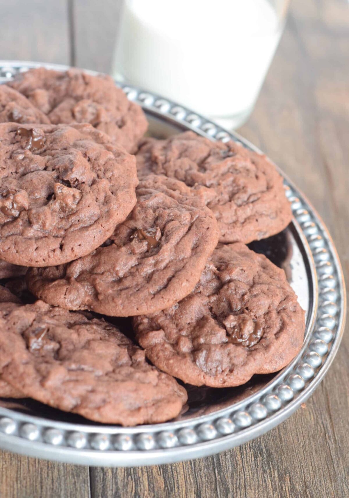 Chocolate cookies with chocolate chips. Plate of them and glass of milk