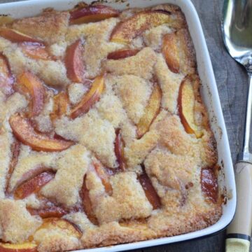 Nectarine cobbler in square blue dish with antique spoon
