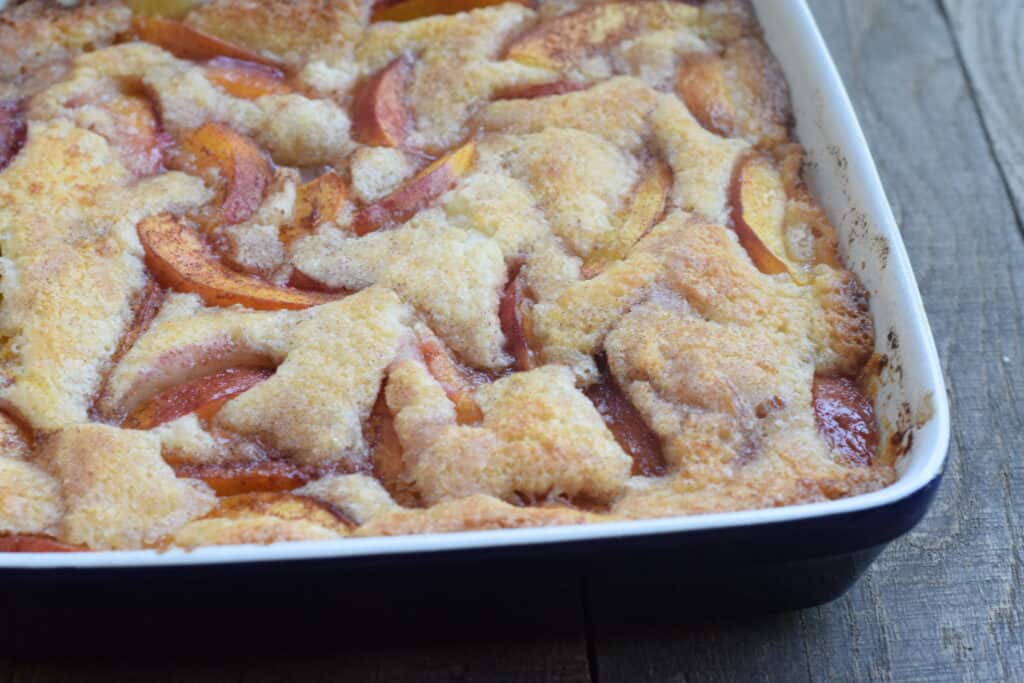 Nectarine cobbler in blue square dish on wooden surface