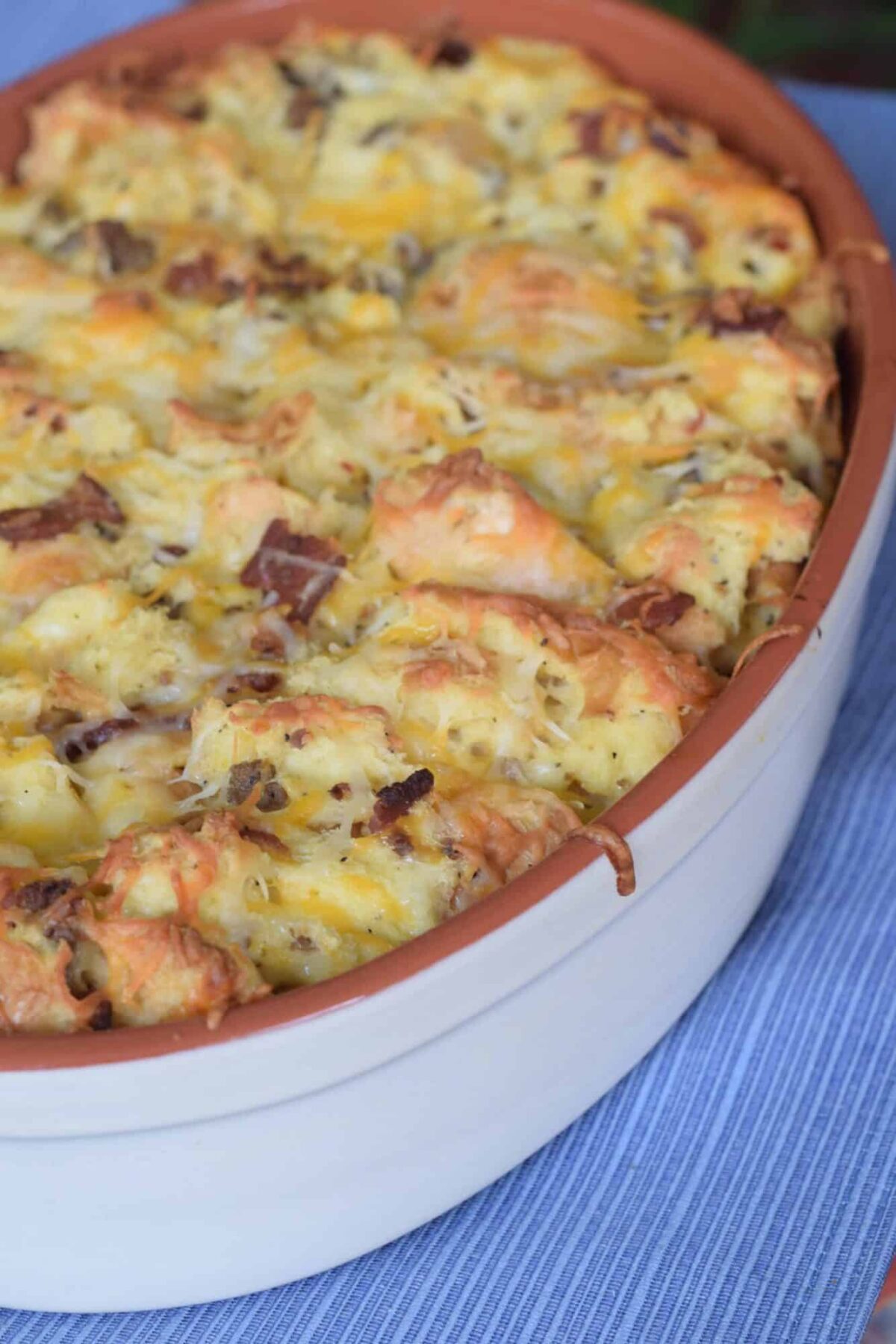 Bacon Sausage Strata in stoneware casserole on blue placemat