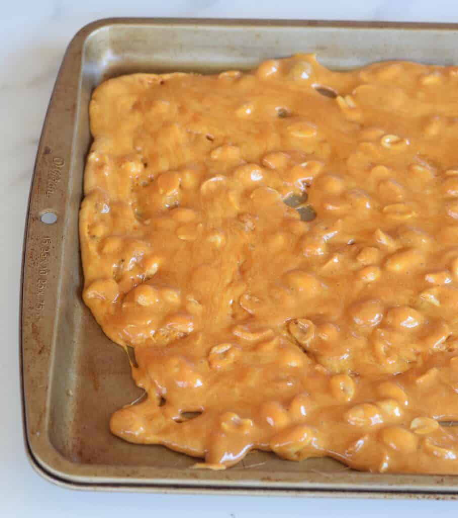 Microwave Peanut Brittle spread immediately into a buttered baking sheet after stirring in peanuts.