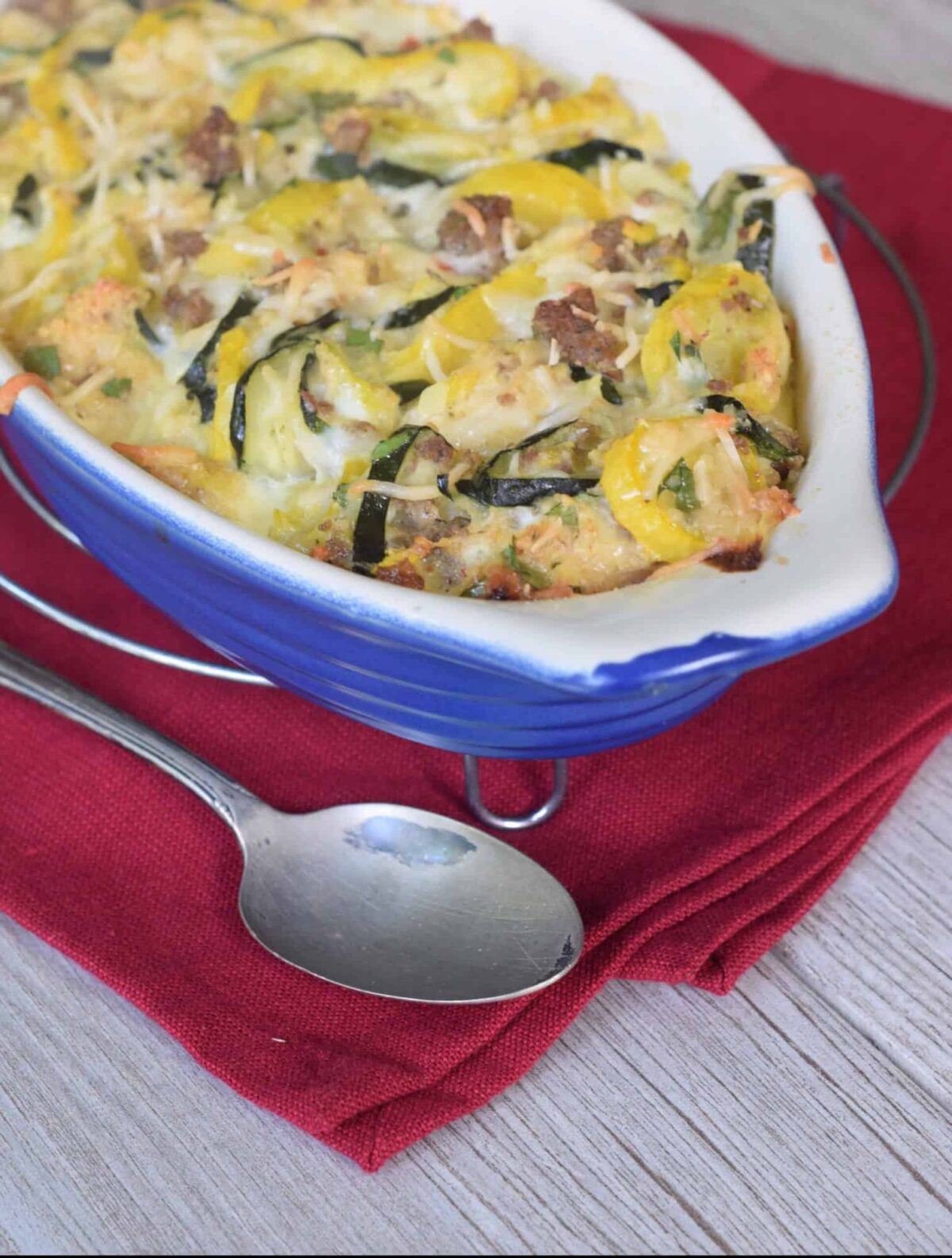 Squash and Sausage Casserole in blue casserole dish on red napkin