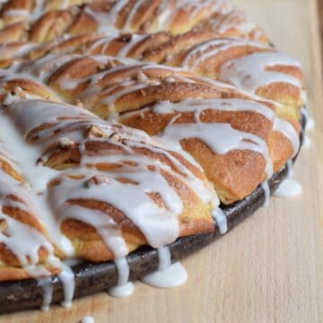 twisted sweet rolls with icing dripping over the side of round pan