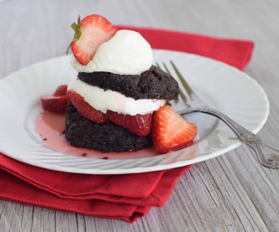 Chocolate Biscuit Strawberry Shortcake on a white plate on a red napkin with a fork on plate.