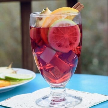 Cranberry juice and fruit in a wine glass on white napkin.