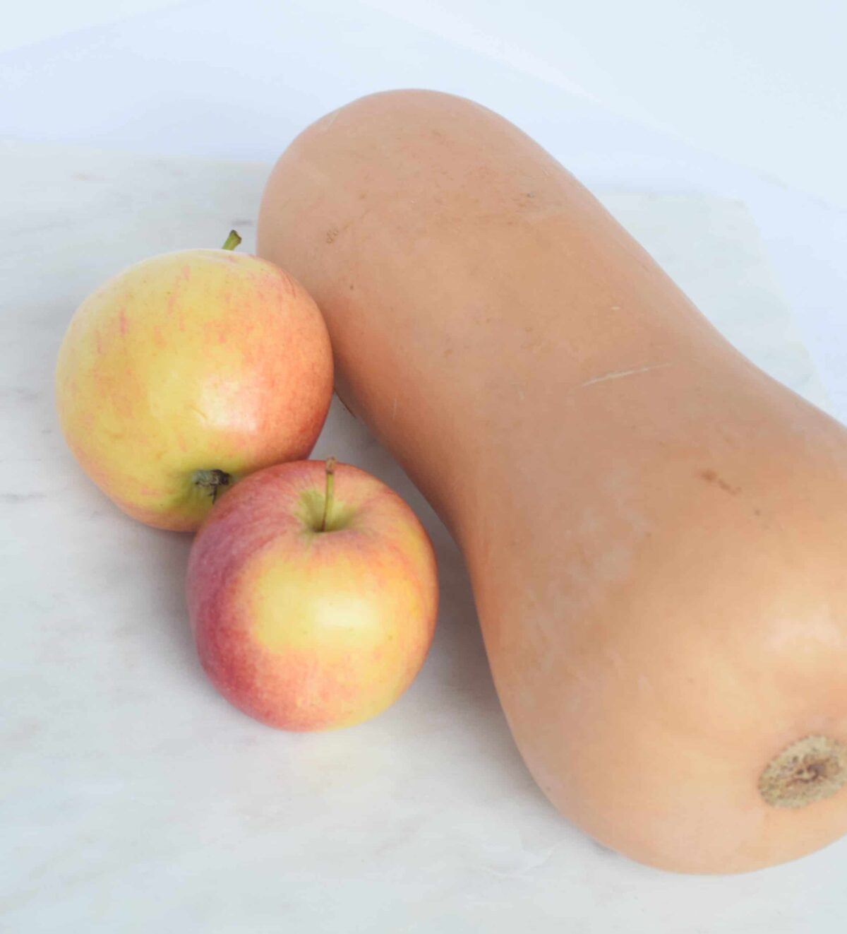 butternut squash on marble with two apples