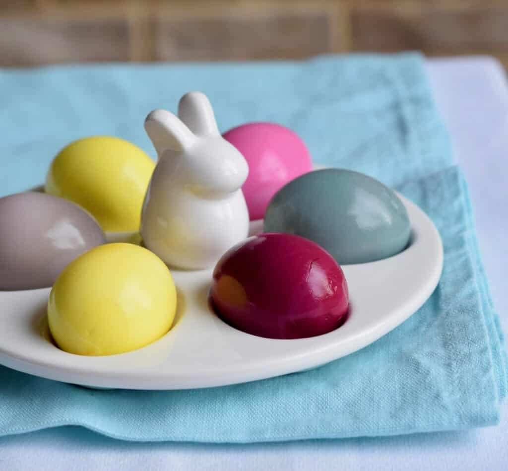 Porcelain white egg plate with a bunny in the middle and colorful dyed eggs.