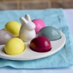 Porcelain white egg plate with a bunny in the middle and colorful dyed eggs.