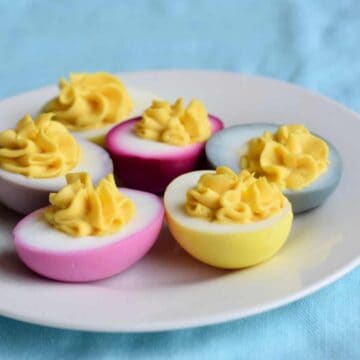 pink yellow blue deviled eggs on white plate