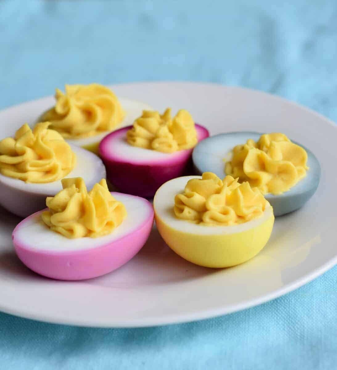 pink yellow blue deviled eggs on white plate