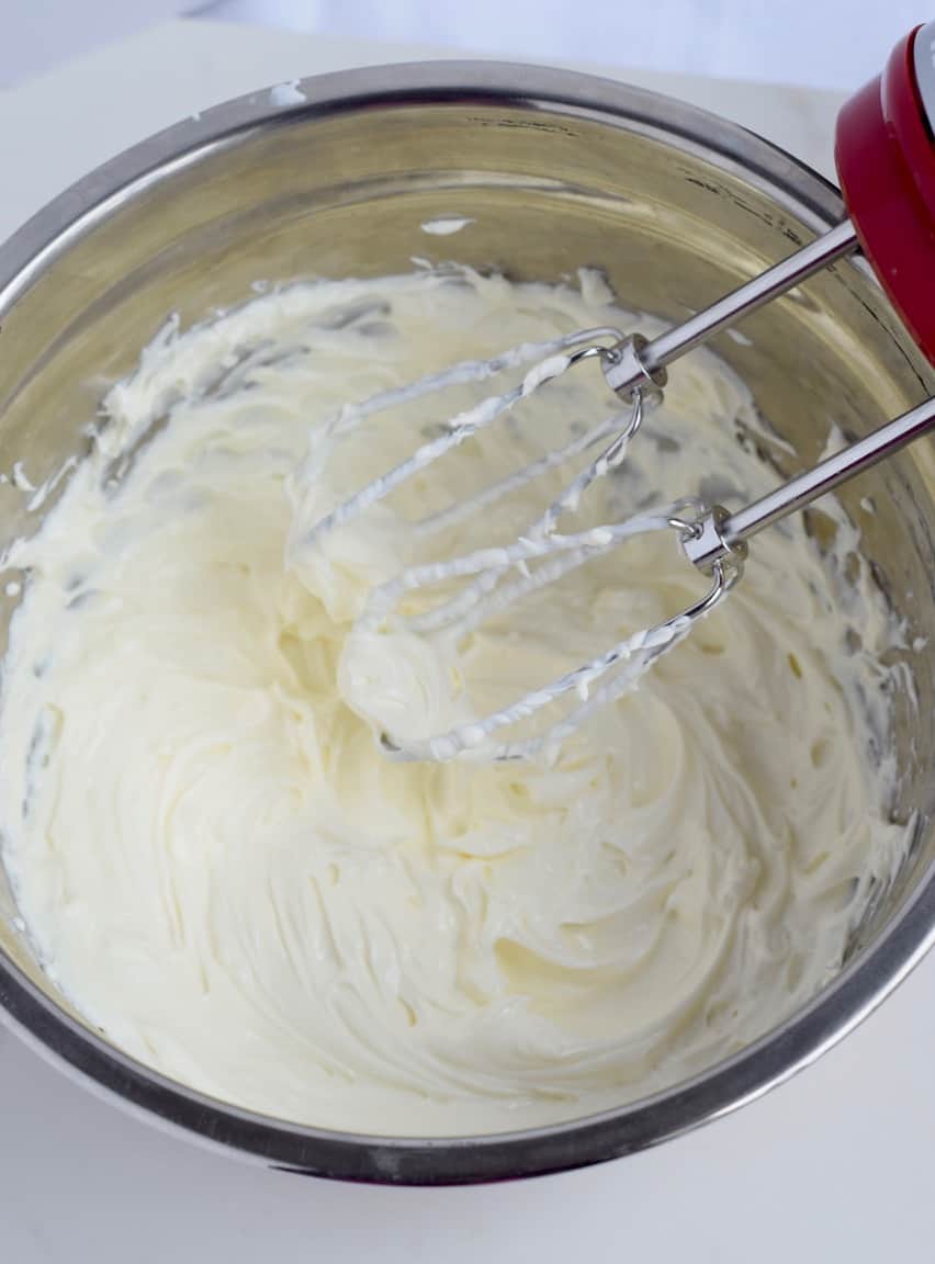 Beaten softened cream cheese with a mixer in a mixing bowl