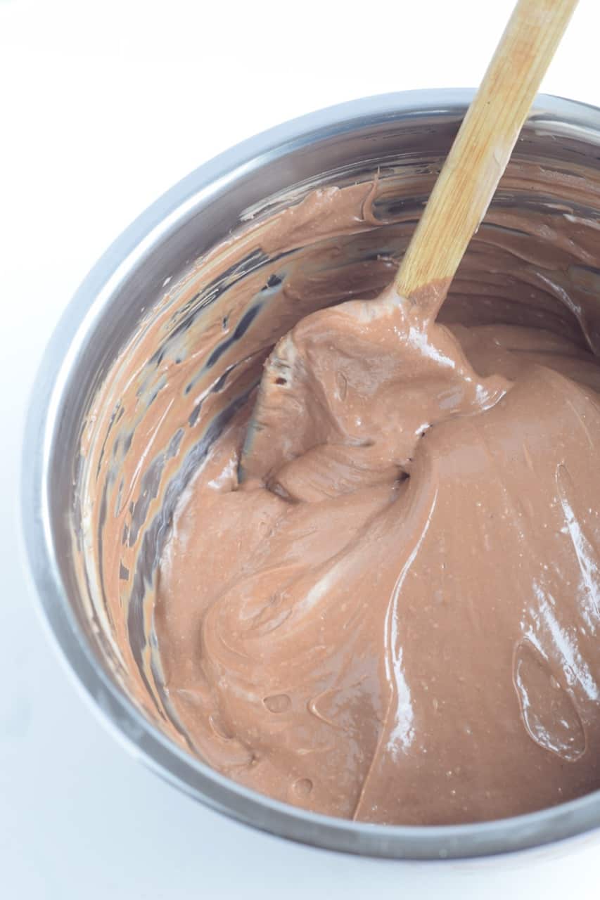 chocolate cheesecake batter in a mixing bowl with spatula