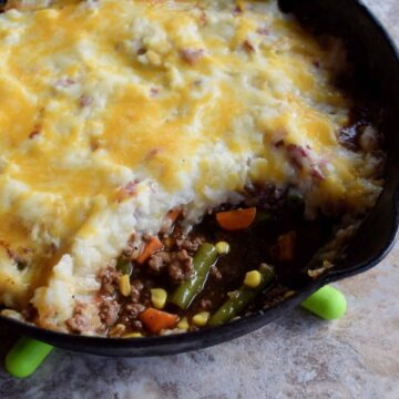 shepherds pie in a cast iron skillet with serving scooped out
