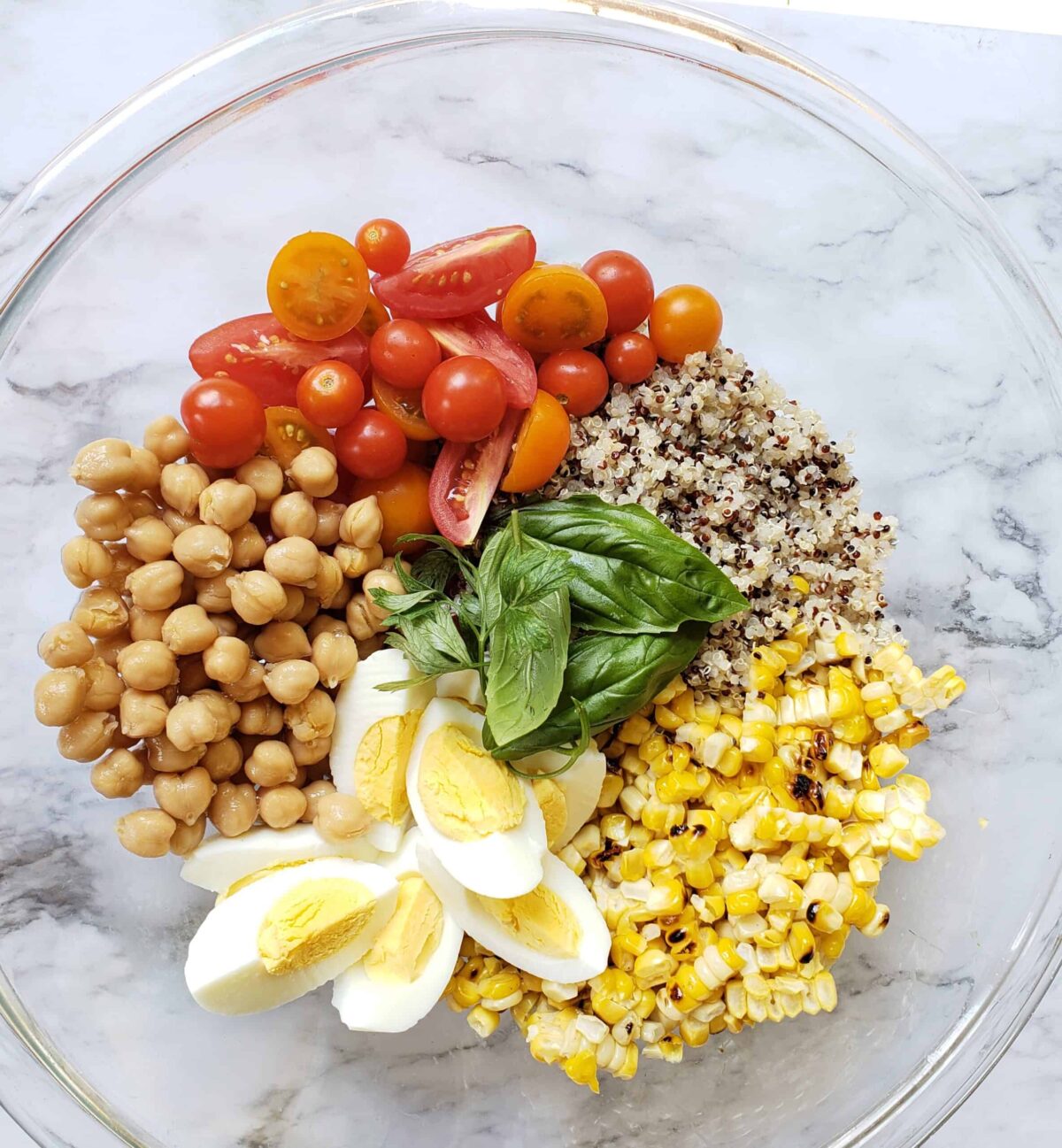 Quinoa, chick peas, Instant Pot cooked eggs, tomatoes, roasted corn, basil in mixing bowl not mixed together