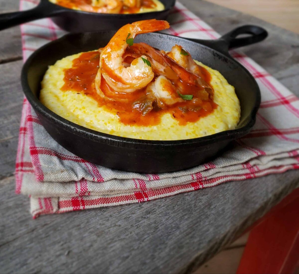 Shrimp and Gouda grits in cast iron skillets on a wooden table