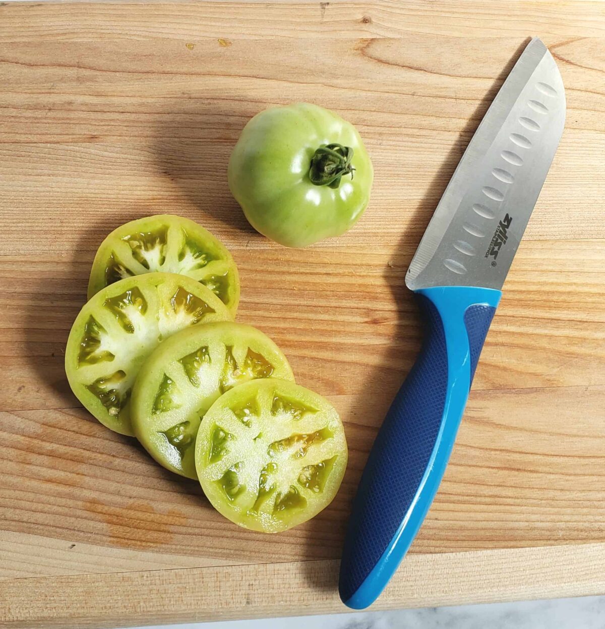 Sliced green tomatoes with knife on cutting board