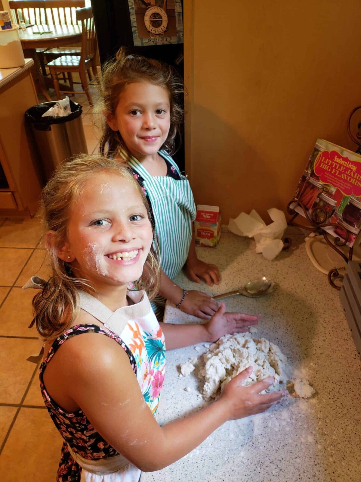 Two girls pressing together biscuit dough on countertop