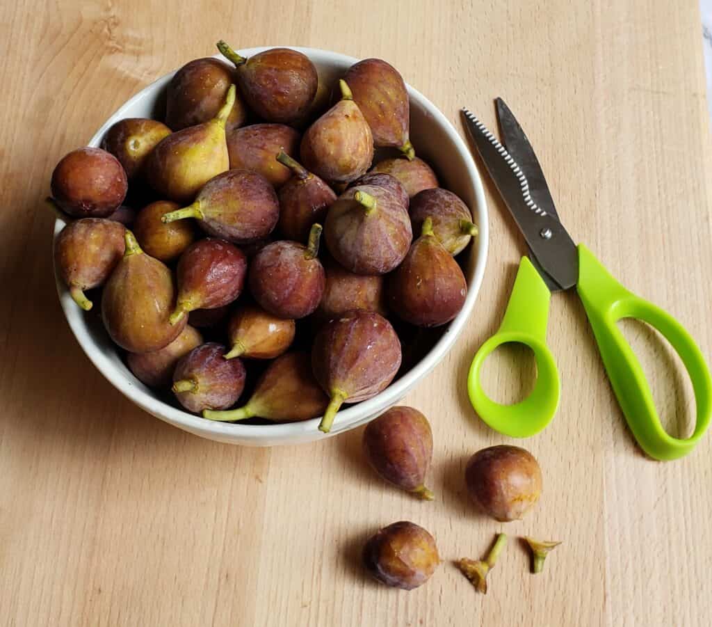 Bowl of small mission figs with stems snipped off with scissors