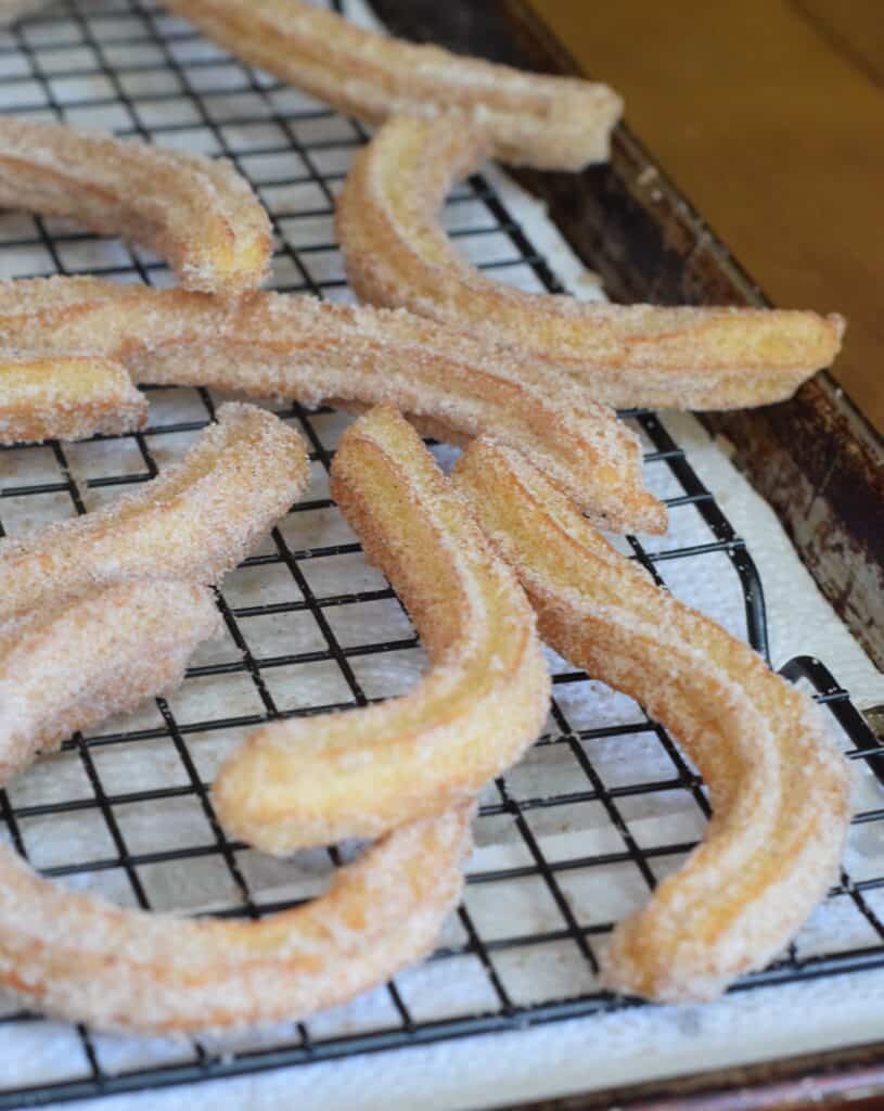 Churros cooling on a wire rack over parchment paper