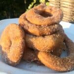 Cinnamon sugar coated and battered fried apple rings on a white plate