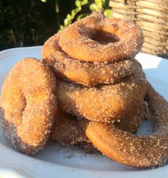 Cinnamon sugar coated and battered fried apple rings on a white plate