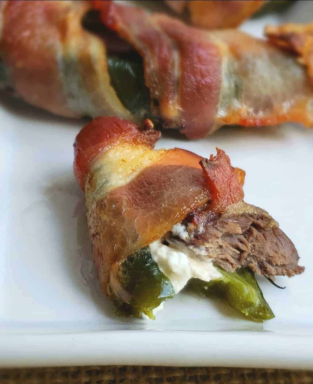 Bacon Wrapped Dove and Jalapeno poppers close up with a yummy bite taken