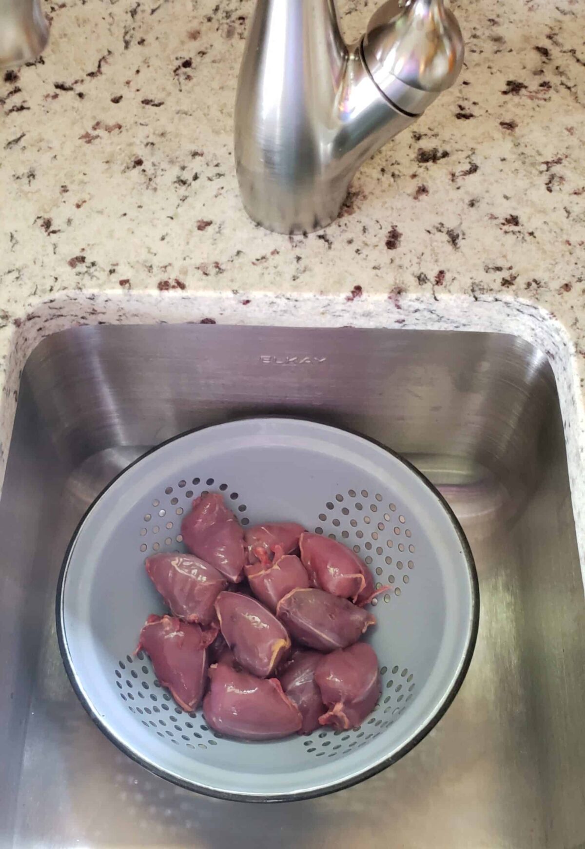 Uncooked dove breasts in colander in sink