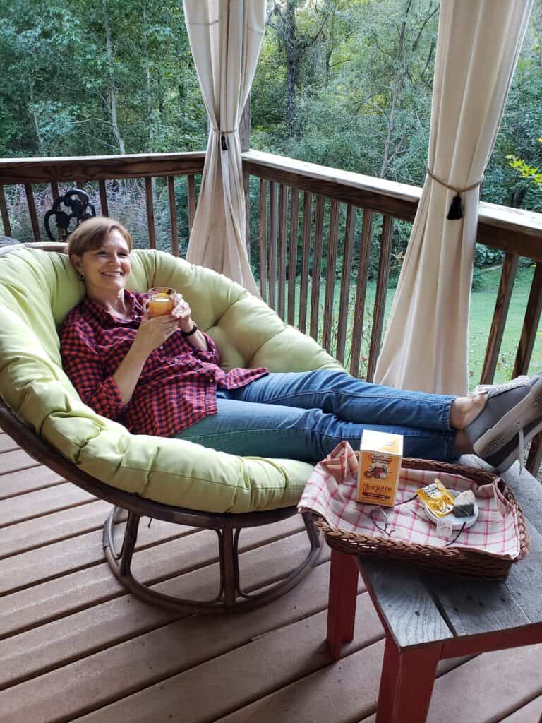 Woman sitting in chair Mulled Sweet Tea Apple Cider on a deck in green papasan chair