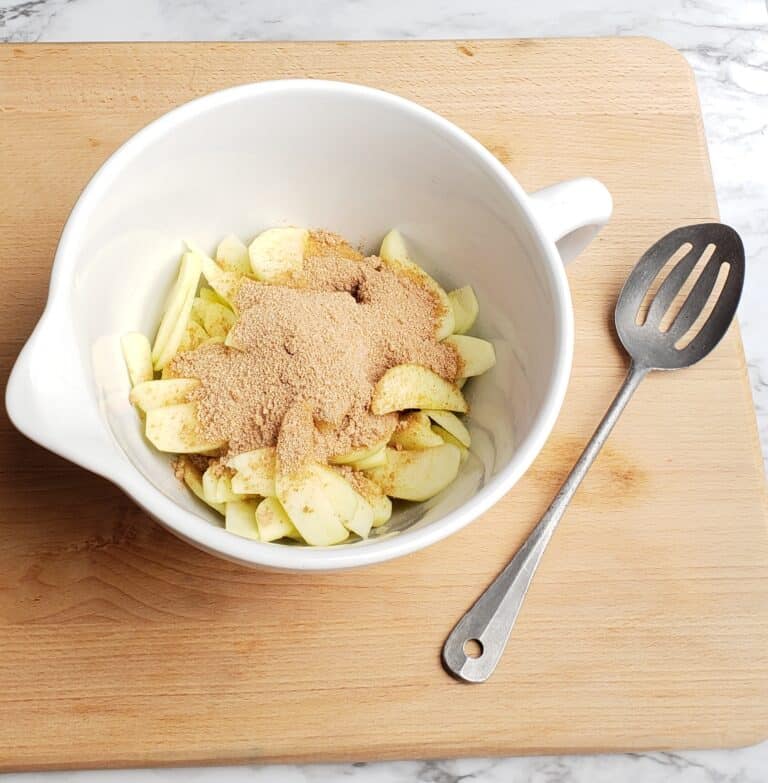 apple galette dumped cinnamon mixture in apple bowl