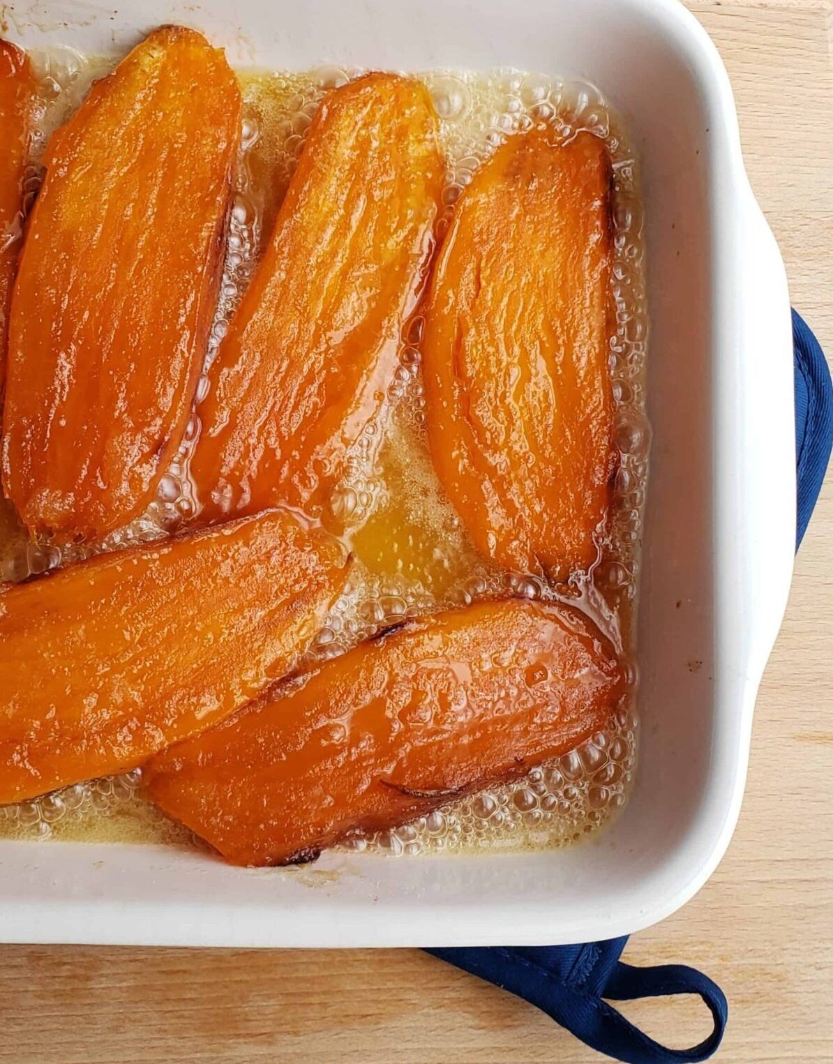 sweet potatoes cut in half lengthwise candied in white casserole dish. Southern side dish