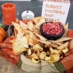 Cranberry Apple Jalapeno Salsa in a black salsa dish with with homemade cinnamon sugar tortilla chips in a decorative fall napkin and a sign that says Turkey, Football, Nap, Repeat