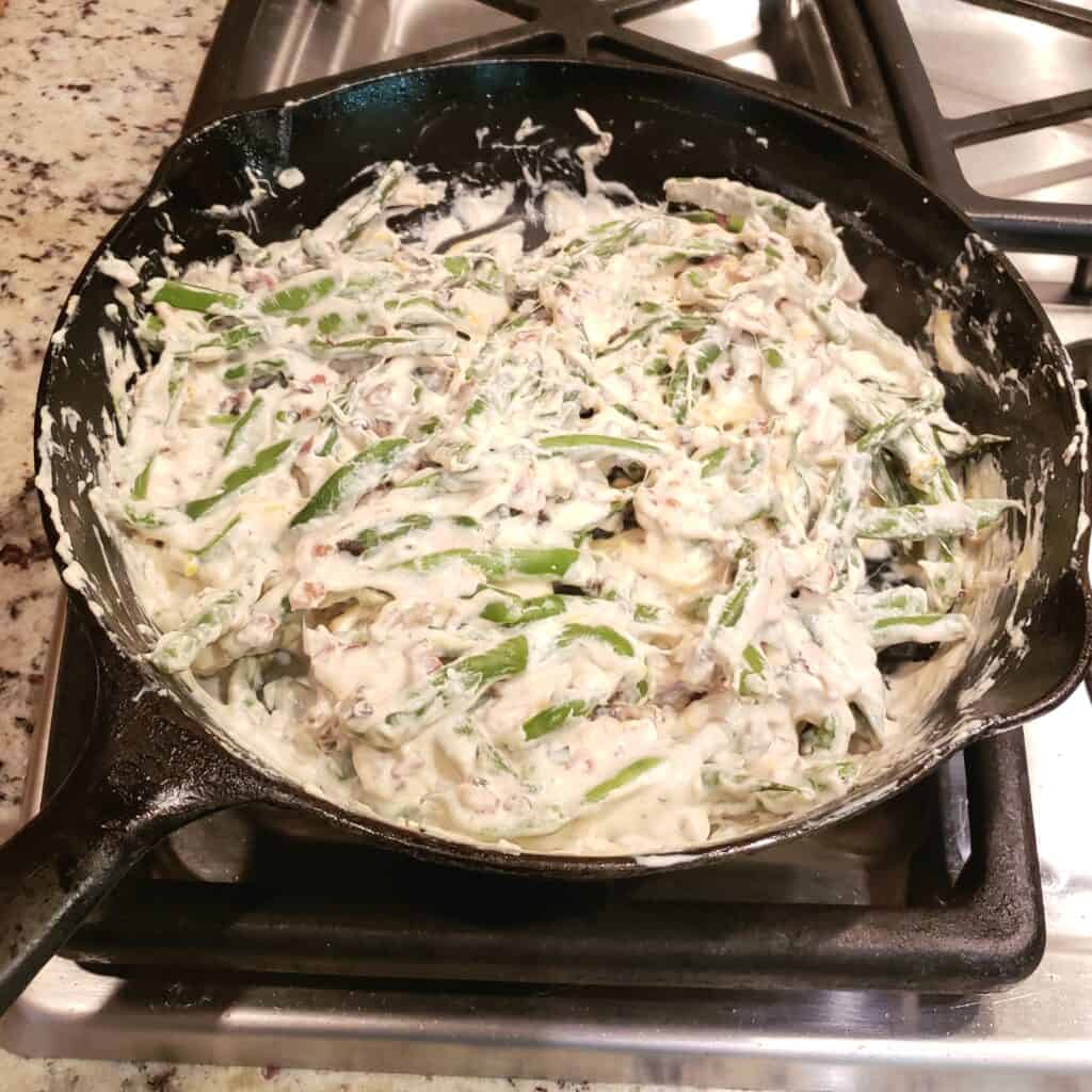 Fresh green beans stirred in to cream cheese and mushrooms in a cast iron skillet