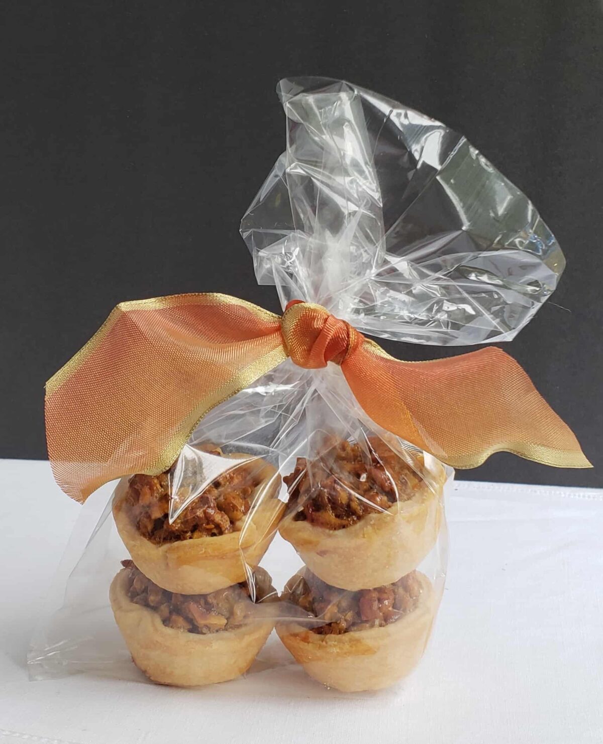 Four Maple Pecan Tassies wrapped in a clear bag with an orange bow