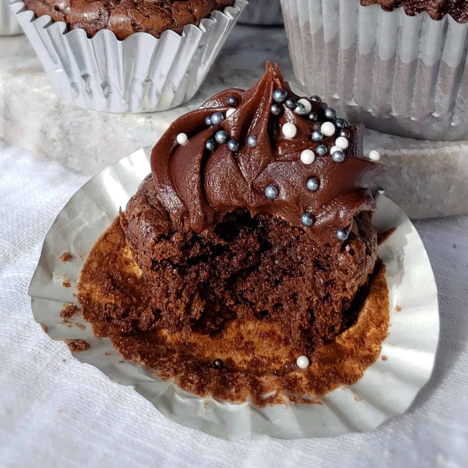 mini brownie cupcake with silver and white sprinkles; a bite taken out