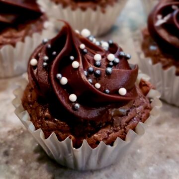 Mini frosted brownie bite in silver paper cup and white and silver sprinkles on top.