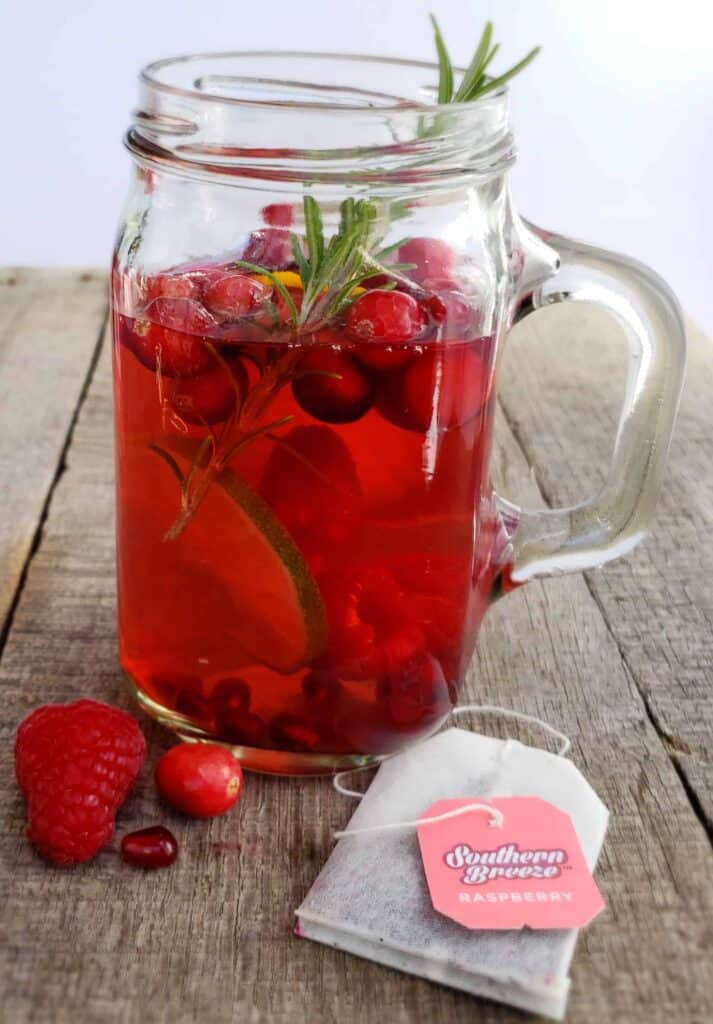 Sweet Tea Sangria Skinny Mocktail is your answer to a holiday drink without the alcohol! The tannins in tea mimic the tannins in red wine plus it is only 5 calories! Served in a mason jar with a handle on a wooden surface.