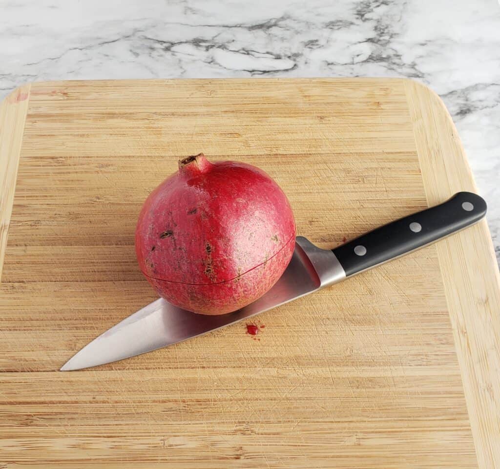 How to remove pomegranate seeds easily. First score the pomegranate in half with a sharp knife