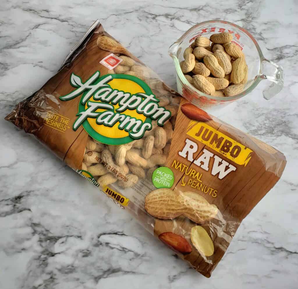 Hampton Farms raw peanuts in a bag with some in a glass bowl on a granite countertop