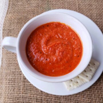 tomato soup in white cup on white saucer with saltines