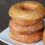 Stack of 3 glazed yeast donuts on a white plate