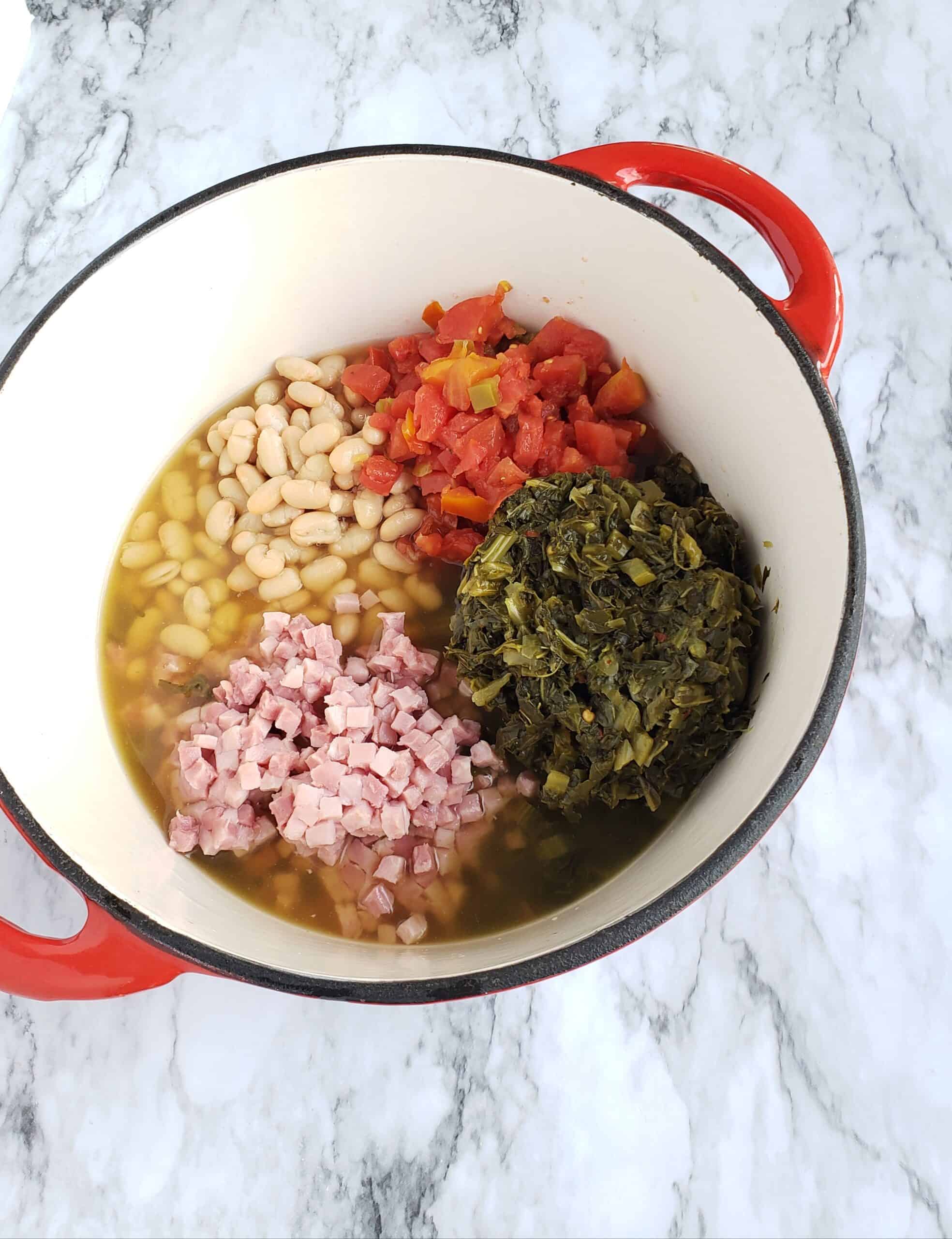 Piles of great Northern beans, turnip greens, ham, and Rotel tomatoes in a red cast iron