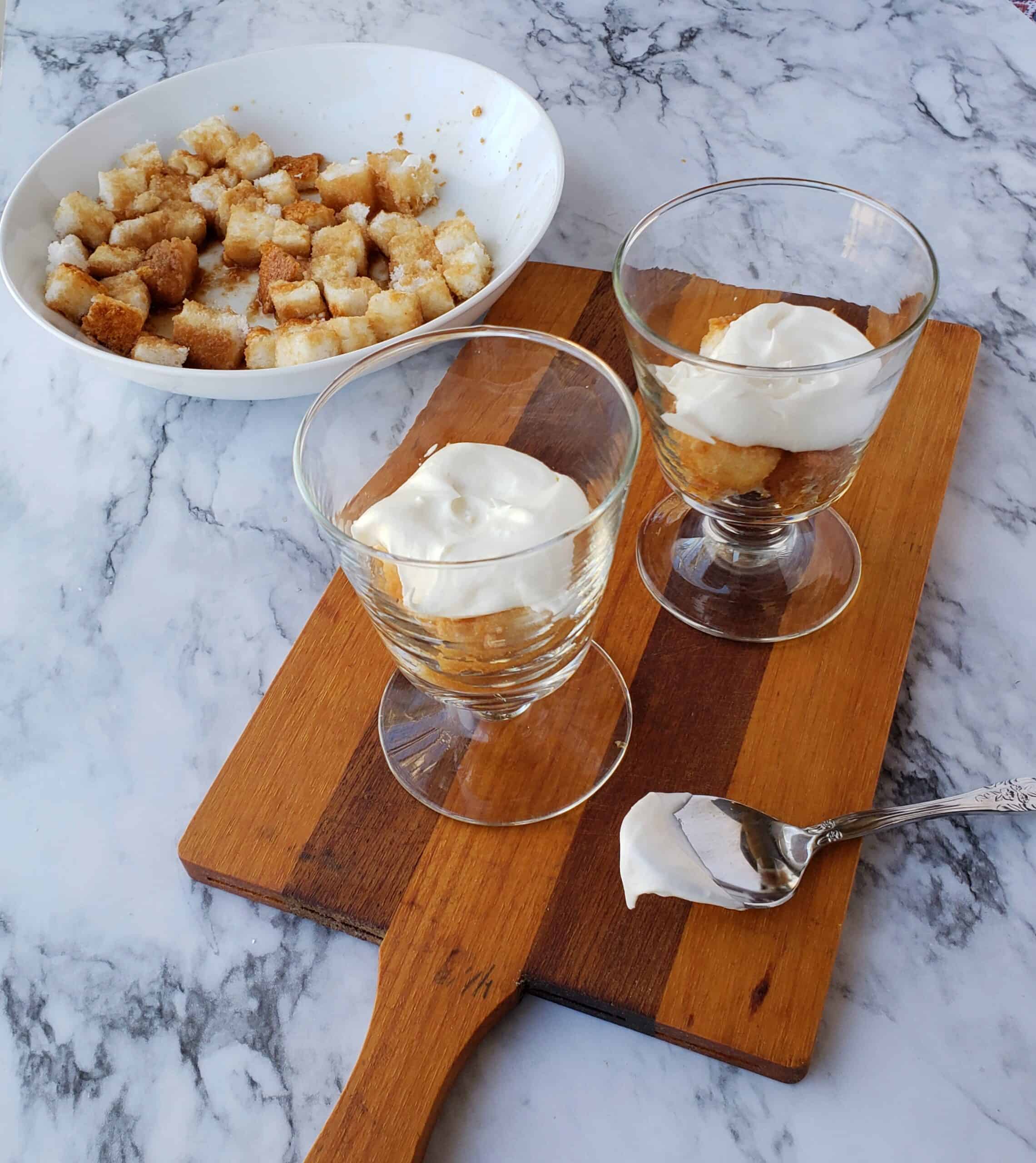 Layer sweet tea soaked cake cubes in small dessert dishescreamy Neufchatel mixture on wooden cutting board