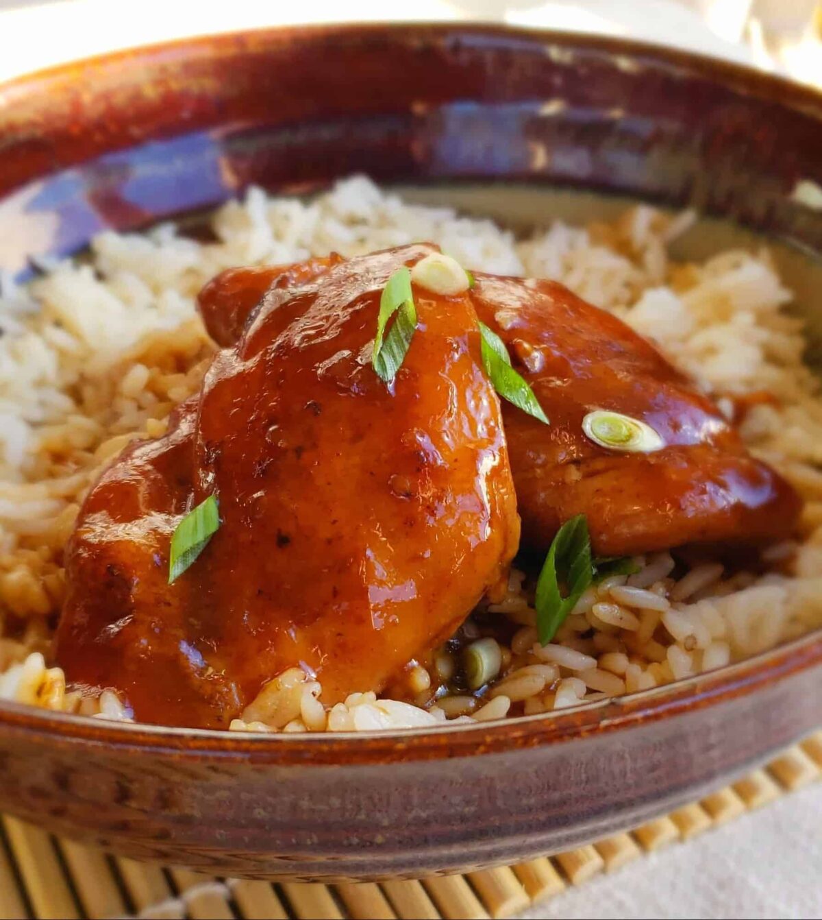 Instant Pot Teriyaki Chicken Thighs is so easy, impressive and yummy! Served over rice in a pottery bowl and garnish with green onions