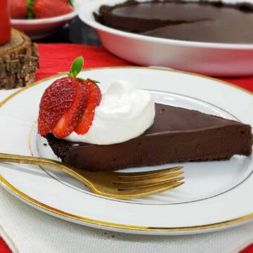 Shortcut Chocolate Truffle Tart is easy as pie...and tastes even better! 4 ingredients and 5 minutes to prep served with whipped cream, a strawberry. Served on white china with gold trim and a gold fork.