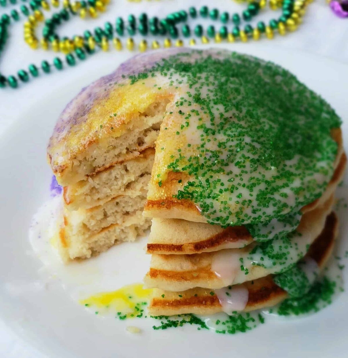 King Cake Pancakes drizzled with icing and green and purple sanding sugar