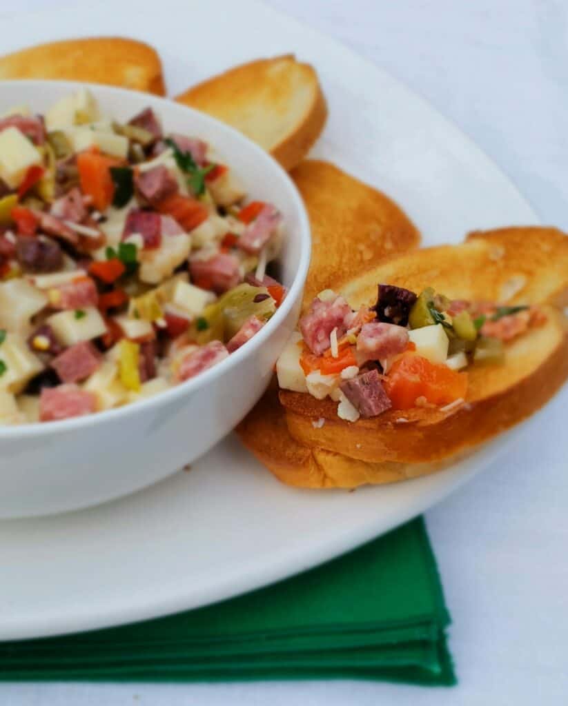 Muffaletta Dip is perfect served with French bread crostini for any occasion not just Mardi Gras or Fat Tuesday