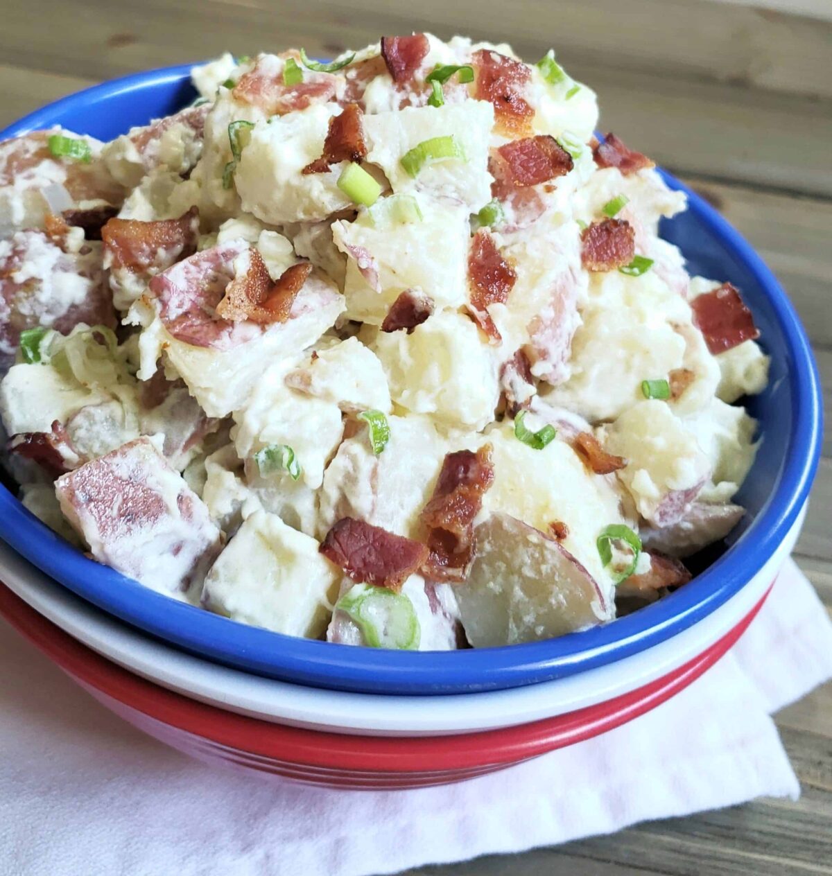 Sour Cream and Green Onion Potato Salad in a stack of 3 red, white and blue bowls on white cloth