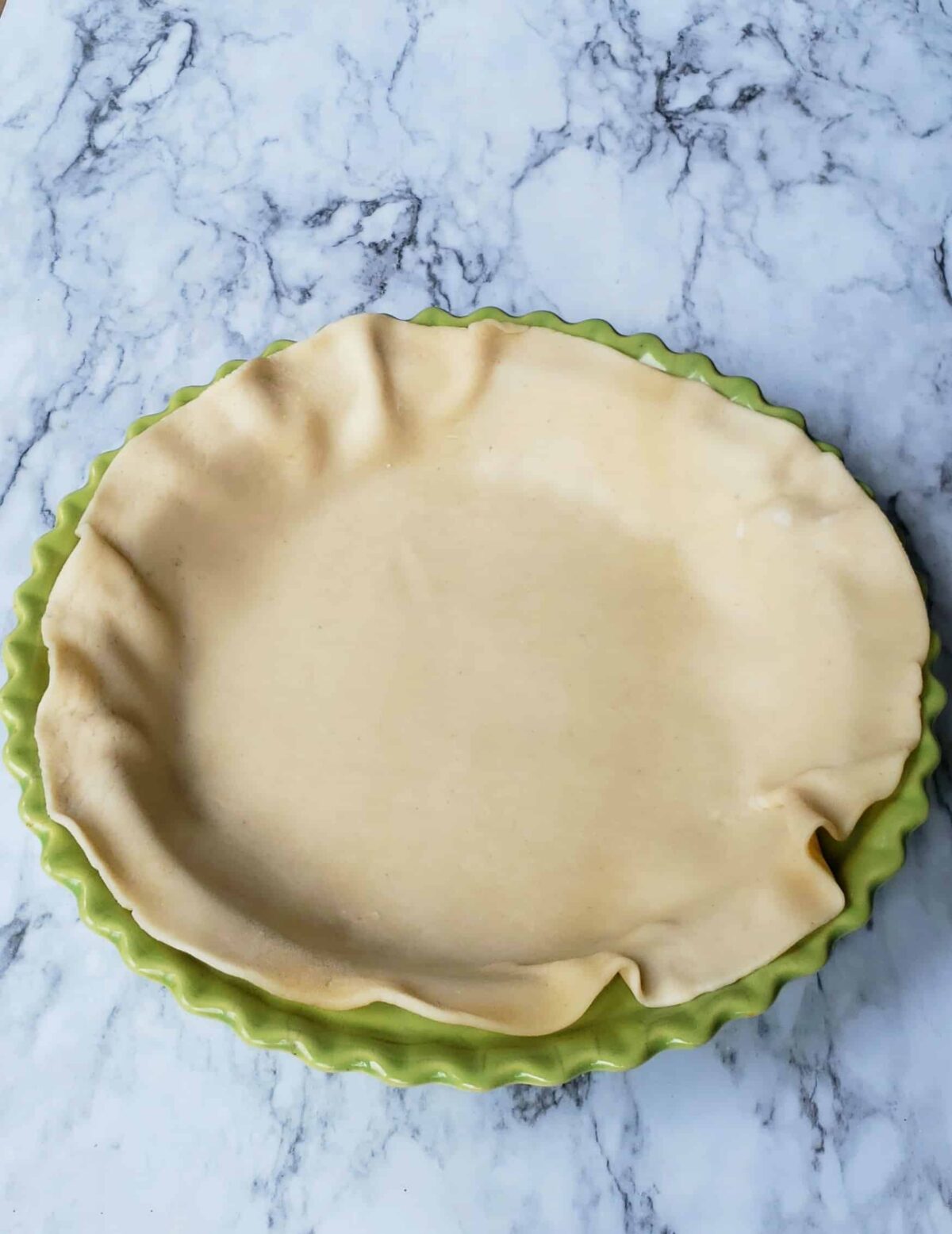 Fitted the pie crust into the bottom of a green pie plate.